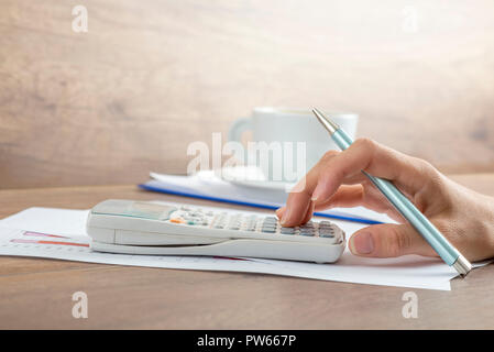 Vue latérale d'un calcul comptable femelle sur une calculatrice manuelle. Banque D'Images