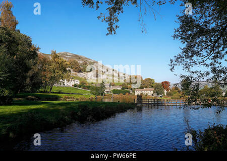 Kilnsey lacs de pêche de truites avec le village en arrière-plan avec la falaise s'élevant au-dessus de Banque D'Images