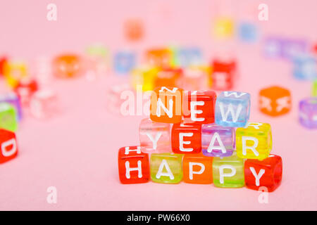 Mots bonne année faite de blocs de lettres colorées sur fond rose. Mise à plat, vue de dessus - vacances, hiver, Noël et nouvel an fête con Banque D'Images