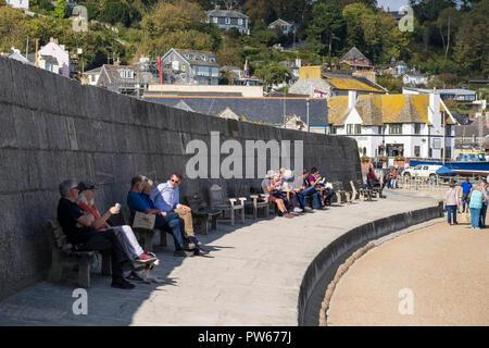 Des gens assis et reposant sur le Cobb dans la ville côtière de Lyme Regis dans le Dorset. Banque D'Images