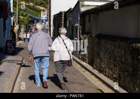 Un couple en train de marcher le long d'une rue dans la ville côtière de Lyme Regis dans le Dorset. Banque D'Images