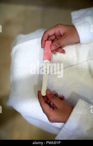 Jeune femme contrôle kit test de grossesse dans la salle de bains Banque D'Images