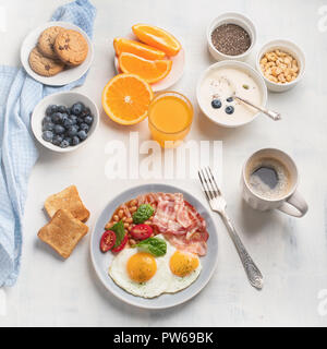 Petit-déjeuner avec les œufs, bacon, jus d'orange, yaourt et du pain grillé. Mise à plat Banque D'Images
