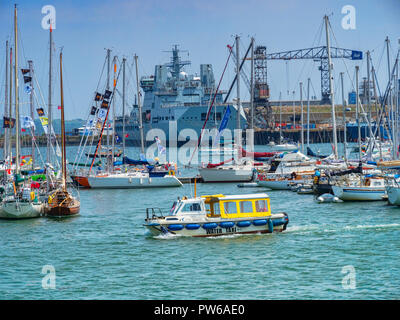 12 Juin 2018 : Falmouth, Cornwall, UK - Taxi de l'eau traversant le port de Falmouth, avec un fond de bateaux et un bâtiment de guerre à quai. Banque D'Images