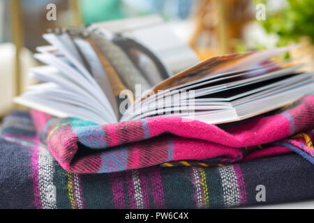 Couverture tartan livre ouvert sur une table de jardin à l'extérieur des maquettes, flatlay concept timeout, hygge, style de vie facile, meilleure vie brouillée détendue relaxant Banque D'Images
