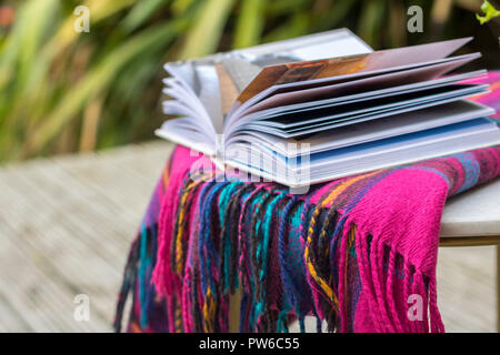 Couverture tartan livre ouvert sur une table de jardin à l'extérieur des maquettes, flatlay concept timeout, hygge, style de vie facile, meilleure vie brouillée détendue relaxant Banque D'Images