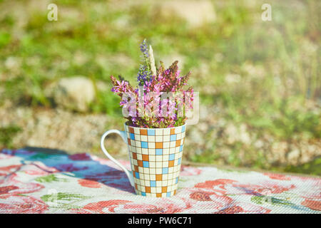 Un petit bouquet de fleurs sauvages est sur la table dans la tasse Banque D'Images