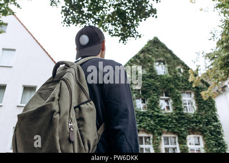 Un touriste se rend à la maison d'hôtes ou à l'auberge afin de rester dans une chambre qu'il a réservé ou un étudiant avec un sac à dos revient à la maison après ses études à l'institut ou en vacances. Banque D'Images