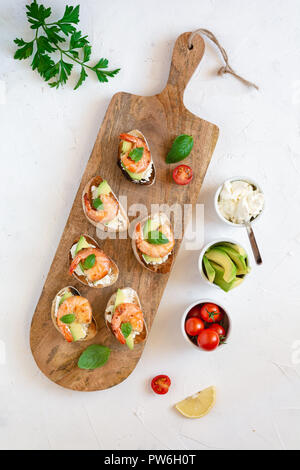 Snack-sandwiches italiens Bruschetta aux crevettes, avocat et fromage décoré par le basilic. Banque D'Images