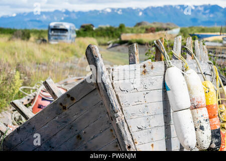 Bateau abandonné avec rusty et bouées altérés le long de l'Homer Spit en Alaska. Vieux bus abandonné en arrière-plan, volontairement floue Banque D'Images