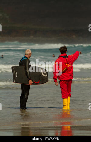 Lifeguard et surfer sur la plage de Cornouailles Banque D'Images