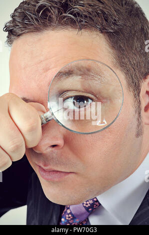 Businessman en costume à travers une loupe isolated on white Banque D'Images