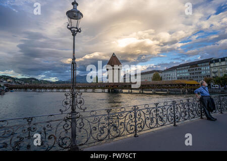 Un vieil homme à la recherche de le coucher du soleil sur le Kapellbrücke à Lucerne, Suisse Banque D'Images