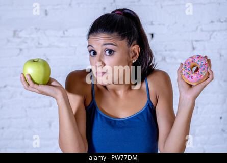 Belle jeune femme doute de passer faire choix entre Apple et donut dans des aliments mauvais pour la santé, l'alimentation, les calories et detox diet concept. Banque D'Images