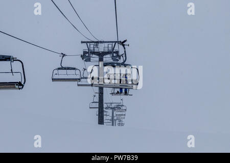 Un surfeur solitaire assis complètement seul dans un télésiège. Le froid brouillard est de faire cette randonnée très inconfortables. Prises à Tignes Banque D'Images