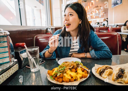 Belle expérience de voyageur que la culture américaine. young girl eating nourriture Américaine et assis dans le restaurant American diner. dans la région de concept. Banque D'Images