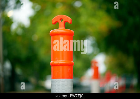 Une ligne d'orange et blanc sur une des bornes de la circulation rue de banlieue arborée. Banque D'Images