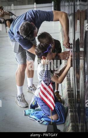 Une famille utiliser un morceau de papier et crayon pour copier un nom de la Mobile Vietnam Memorial Wall, également connu sous le nom de mur AV, après une cérémonie au cours de l'épinglage 2017 Marine Corps Air Station Miramar Air Show au MCAS Miramar, Californie, 23 septembre. Mur AV bénévoles, membres de la famille et le service actif les membres de service donné épinglettes pour les anciens combattants du Vietnam pour commémorer leur service et exprimer ma gratitude. "Le 2017 MCAS Miramar Air Show permet au public et aux membres actuels de l'occasion pour remercier les anciens combattants de la guerre du Vietnam, a déclaré le Colonel Jason Woodworth, commandant des MCM M Banque D'Images