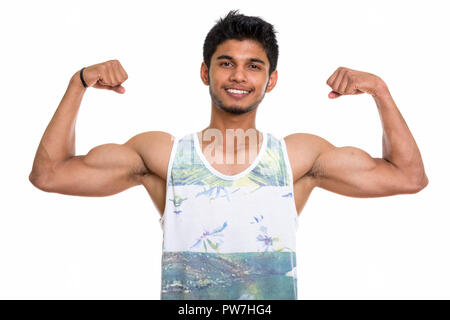 Studio shot of young happy Indian man smiling lors de la torsion à la fois Banque D'Images