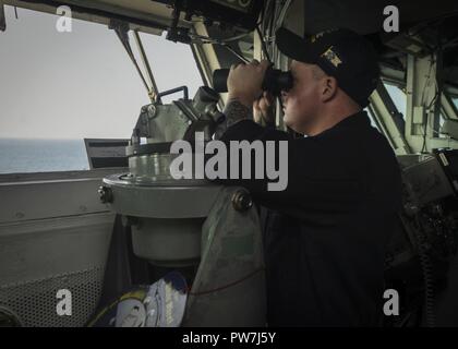 Le Golfe Arabique (sept. 23, 2017) La Marine américaine maître de Manœuvre 2e classe Adam Tabor, Cincinnati, forme utilise les jumelles dans le pont à bord du porte-avions USS Nimitz (CVN 68), 23 septembre 2017, dans le golfe Arabo-Persique. Nimitz est déployée dans la 5e flotte américaine zone d'opérations dans le cadre de l'opération inhérents résoudre. Alors que dans cette région, le navire et d'attaque mènent des opérations de sécurité maritime pour rassurer les alliés et les partenaires, de préserver la liberté de navigation, et de maintenir la libre circulation du commerce. Banque D'Images