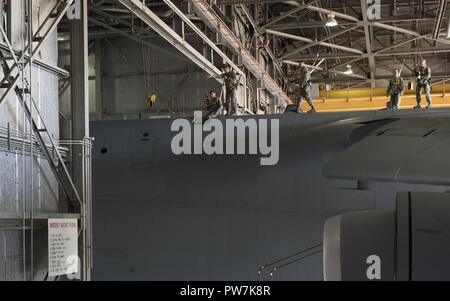 U.s. Air Force Airmen entrez une berline haut de la côté d'un C-5M Super Galaxy garée dans un hangar pour l'entretien, 22 septembre 2017, Travis Air Force Base, en Californie de la maintenance du 660 e Escadron de maintenance des aéronefs sont responsables de la sécurité et la fiabilité de l'leet, renforçant ainsi la puissance aérienne américaine à travers le monde. Banque D'Images