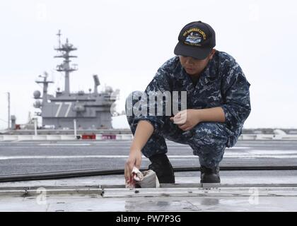 La NORFOLK (sept. 26, 2017) l'Aviation maître de Manœuvre (Équipement) apprenti aviateur Joyce Trinité nettoie une catapulte dans le poste de pilotage de la classe Nimitz porte-avions USS ABRAHAM LINCOLN (CVN 72). Abraham Lincoln est mouillée à Norfolk et se tient prêt à répondre à la mission de la Marine américaine. Banque D'Images