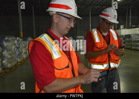 Patrick Trèves et Lucius Duerksen, tous deux de l'US Army Corps of Engineers, District de Kansas City synchroniser leurs applications sur leur téléphone cellulaire pendant le contrôle de palettes de matériel toit bleu pour le stock à un entrepôt local à Miami, Floride, avant de le déployer sur le terrain. Trèves et Duerksen sont un inspecteur de la qualité et toit bleu objet experts déployés en Floride à l'appui de l'ouragan l'Irma. Des centaines d'employés du USACE de partout dans le monde sont en service dans la Floride, Puerto Rico ande les îles Vierges américaines. (USACE Banque D'Images