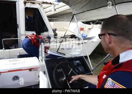 L'équipage de la Garde côtière canadienne avec les Florida Keys de la Direction générale de la fonction de soutien en cas d'urgence 10 Floride place une évaluation autocollant sur la coque d'un navire de personnes déplacées par le cyclone Irma dans Boot Key Harbour, près de Marathon, en Floride, le 29 septembre, 2017. Banque D'Images