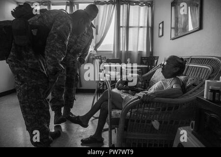 Le sergent de l'armée américaine. Luis Rodriguez (avant gauche), vol, Medic, et Cpt. Benjamin Stork (retour), médecin de l'air, tous deux assignés à la 101e Brigade d'aviation de combat (cabine), 101st Airborne Division (Air Assault), parler avec Georgina Felix, un résident de l'Edificio Francisco Colon Gordian, un foyer pour personnes âgées, soins de Ceiba, Puerto Rico, 30 septembre 2017. La 101e CAB mène des efforts de secours et d'évacuation médicale à l'appui de la FEMA dans le processus de récupération de Puerto Rico après la dévastation créée par l'Ouragan Maria. Banque D'Images