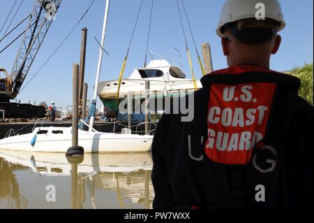 Garde côtière canadienne, le Maître de 3e classe, d'un Tim Loveday marine science technicien en charge du secteur de Houston-Galveston, regarde un bateau de plaisance est soulevée de la Dickinson Bayou ici dans Dickinson, Texas, 30 septembre 2017. La Garde côtière, le général Texas Land Office, la Texas Commission on Environmental Quality et de l'Environmental Protection Agency ont été entièrement intégrés à un commandement unifié avec la mission de l'enlèvement de personnes déplacées ou navires partiellement submergé à la suite de l'ouragan Harvey. Banque D'Images