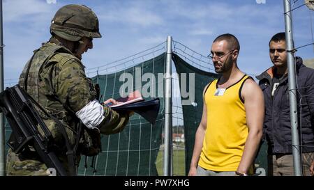 Un soldat espagnol, gauche, écrans civils passant par un terminal au cours d'un exercice d'évacuation de l'ambassade avec les Marines du but Spécial Groupe Force-Crisis Response-Africa air-sol marin près de Asturias, Espagne, le 28 septembre 2017. SPMAGTF-CR-AF déployés pour mener limited d'intervention en cas de crise et théâtre-opérations de sécurité en Europe et l'Afrique du Nord. Banque D'Images