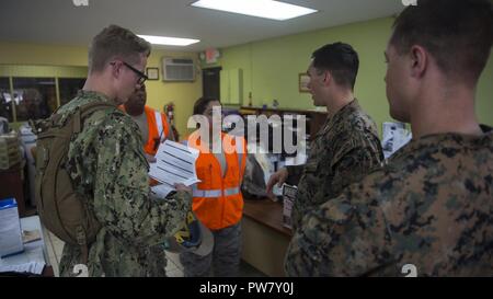 Les Marines américains avec la 26e Marine Expeditionary Unit (MEU) et la marine de marins avec un bataillon de construction 2 amphibie, discuter d'un des centres de distribution locaux dans les procédures d'aide aux municipalités autour de Porto Rico avec Porto Rico Air National Guard Senior Airman Karen Ocasio à l'appui de l'Ouragan Maria les efforts de secours à Canovanas, Porto Rico, 1 octobre, 2017. Le ministère de la Défense soutient l'Agence fédérale de gestion des urgences, le principal organisme fédéral, en aidant les personnes touchées par l'Ouragan Maria afin de minimiser la souffrance et est l'une composante de l'ensemble des respon Banque D'Images