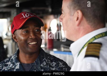 FASLANE (Écosse) (sept. 29, 2017) Le Cmdr. Timothy Moore, commandant de la classe Arleigh Burke destroyer lance-missiles USS Donald Cook (DDG 75), parle avec le pilote écossais que le navire arrive à Faslane, en Écosse, pour un service au port le 29 septembre, 2017. Donald Cook, l'avant-déployé à Rota, en Espagne, est sur sa sixième patrouille dans la sixième flotte américaine zone d'opérations à l'appui des alliés et partenaires, et les intérêts de sécurité nationale des États-Unis en Europe. Banque D'Images