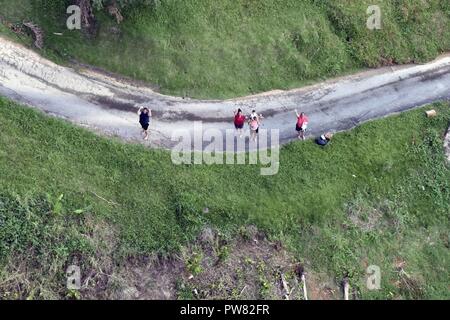 Les habitants de la Garde côtière canadienne à un vague Air Station Borinquen MH-65 de l'équipage de l'hélicoptère Dauphin volant au-dessus d'eux mardi, Octobre 3, 2017, près de Utuado, Puerto Rico. Les sections locales ont été bloqués après l'Ouragan Maria par emporté des routes et des coulées. Banque D'Images