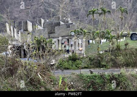 Les habitants de la Garde côtière canadienne à un vague Air Station Borinquen MH-65 de l'équipage de l'hélicoptère Dauphin volant au-dessus d'eux mardi, Octobre 3, 2017, près de Utuado, Puerto Rico. Les sections locales ont été bloqués après l'Ouragan Maria par emporté des routes et des coulées. Banque D'Images