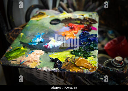 Un gros plan d'une palette d'huile multicolores dans un atelier de peintre. Une palette de l'artiste composé de différents les peintures à l'huile. Huiles essentielles sur une nappe de couleur Banque D'Images