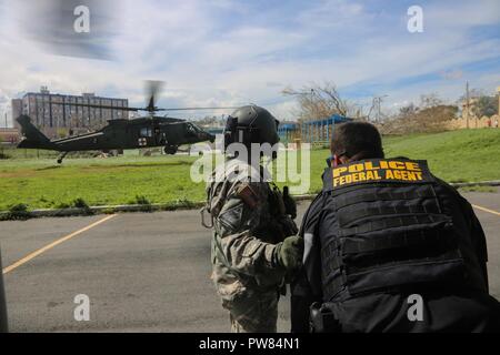 Le sergent de l'armée américaine. Luis Rodriguez, affecté à la 101e Brigade d'aviation de combat (ACR), aide un agent de la police locale d'un HH-60 Black Hawk, Arecibo, Puerto Rico, 30 septembre 2017. La 101e CAB va mener des efforts de secours et d'évacuation médicale à l'appui de la FEMA dans le processus de récupération de Puerto Rico après la dévastation créée par l'Ouragan Maria. Banque D'Images