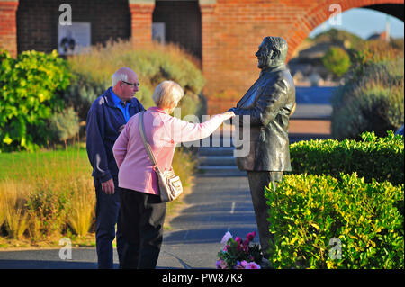 Les femmes d'atteindre la main pour toucher la statue de comédien britannique Les Dawson dans la paix et le bonheur dans le jardin St Annes on Sea, Lancashire, Royaume-Uni Banque D'Images