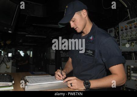 5ème ZONE DES OPÉRATIONS DE LA FLOTTE (nov. 02, 2017)'Aérographe 4400 2e classe Jakob Kenna, originaire de Cocoa Beach, Floride, affecté à la navigation à bord du ministère landing ship dock amphibie USS Pearl Harbor (LSD 52), consigne les informations dans le journal de pont en position debout une montre. Pearl Harbor est déployée dans la zone 5e flotte américaine des opérations à l'appui d'opérations de sécurité maritime visant à rassurer les alliés et les partenaires, et de préserver la liberté de navigation et la libre circulation du commerce dans la région. Banque D'Images