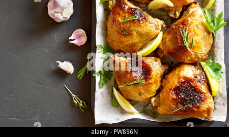 Cuisses de poulet au four sur la plaque de cuisson sur pierre noire arrière-plan. Haut de la vue, télévision lay Banque D'Images