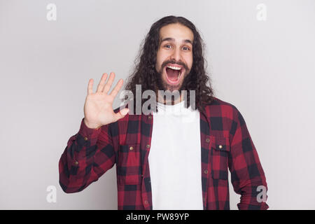 Bonjour, soyez le bienvenu. Heureux l'homme surpris avec barbe et black long cheveux bouclés en chemise rouge à carreaux décontractée standing looking at camera et d'accueil. je Banque D'Images