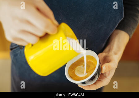 Close up of barista pouring milk à la vapeur en rendant la tasse de café latte art. Banque D'Images