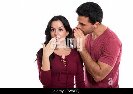 Studio shot of young couple avec l'homme à la femme à chuchoter Banque D'Images