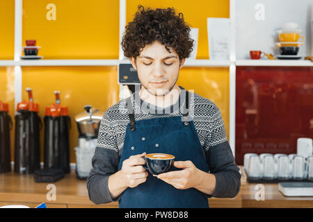 Barista holding Coffee cup près de comptoir de café lumineux et modernes. Banque D'Images