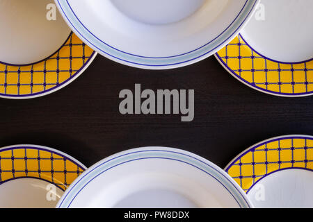 Un fond en bois noir avec trois assiettes vides bleu et blanc et jaune et blanc, trois assiettes vides. Banque D'Images