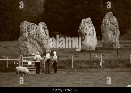 Les gens hommes et femmes marchant autour d'Avebury henge monument néolithique des cercles autour du village d'Avebury dans le Wiltshire, Angleterre, Royaume-Uni Banque D'Images