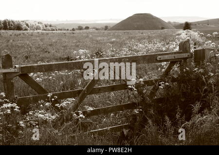 Image en noir et blanc de Silbury Hill Chalk artificiel .monticule préhistorique dans un champ derrière la porte en bois cinq bar près de Avebury Wiltshire England UK Banque D'Images