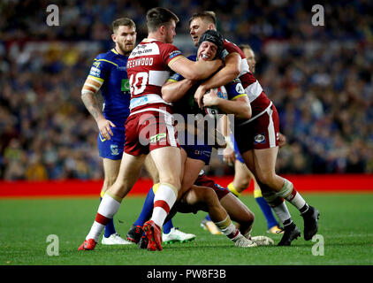 Warrington Wolves' Chris Hill (centre) est abordé par Wigan Warriors' Joe Greenwood (à gauche) et Ryan Sutton (à droite) lors de la Grande Finale de la Super League Betfred à Old Trafford, Manchester. Banque D'Images