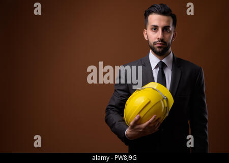 Beau jeune homme d'affaires iranien barbu avec un casque de protection contre Banque D'Images