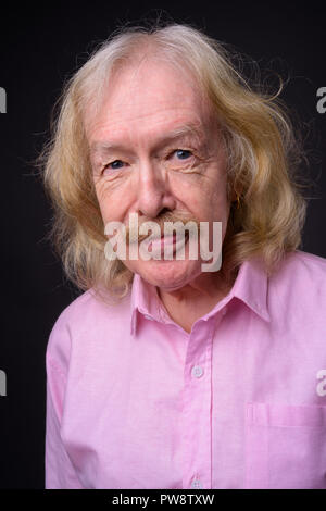 Senior businessman wearing pink shirt contre l'arrière-plan gris Banque D'Images